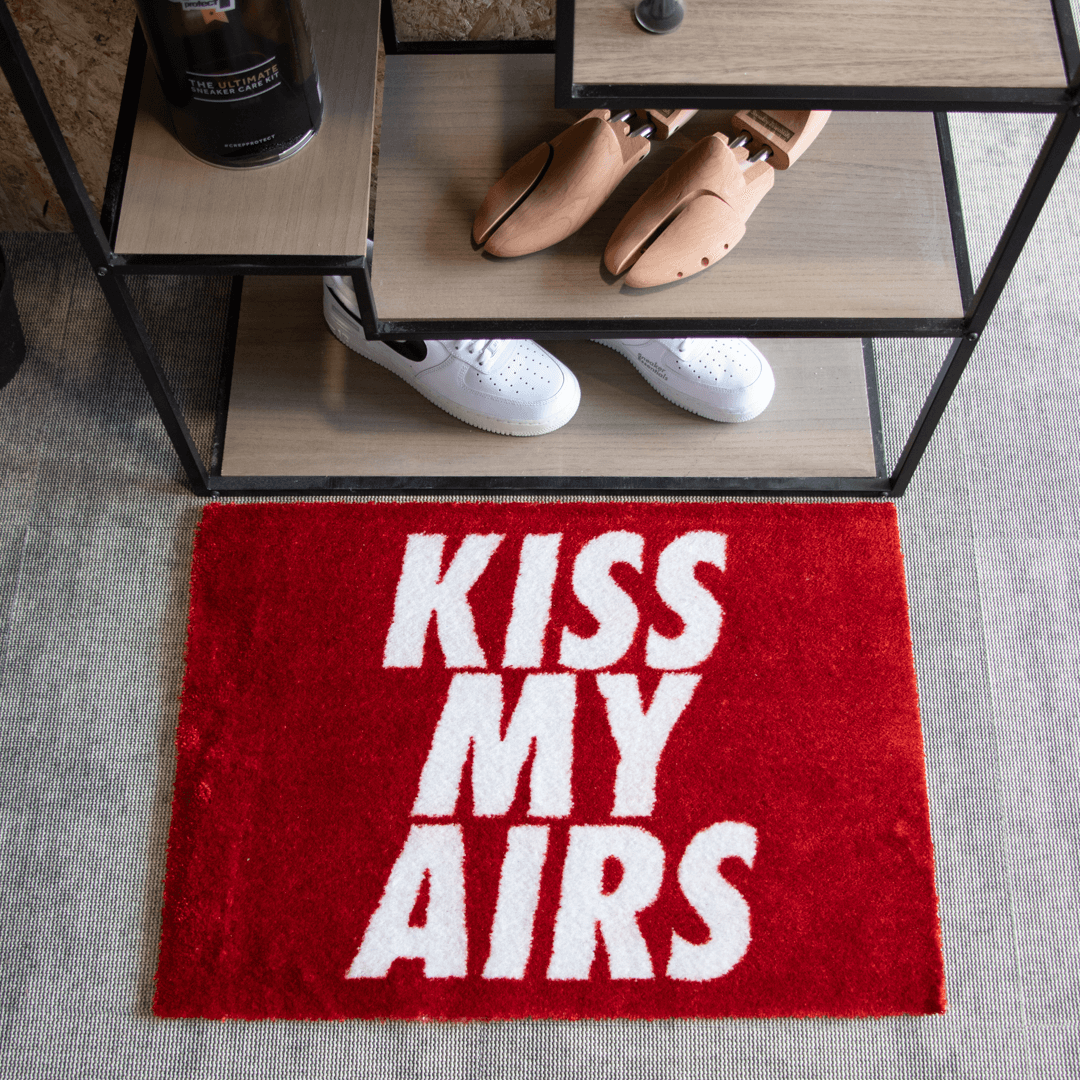 Sneaker vloerkleed Kiss My Airs Rood naast een schoenenrek met sneakers